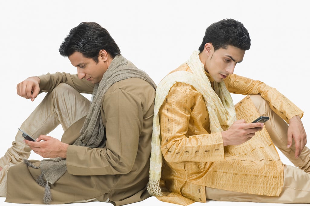 Two men text messaging on mobile phones